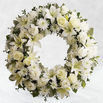 We offer a wreath of white blooms, designed by our florists, in tribute to your loved one and their natural heart and peaceful spirit. This peaceful gesture symbolizes the circle of everlasting life.
<br>Arranged as: 
Round Wreath Arrangement of 20 White Roses, 20 White Carnations, 10 Stems of Sivanthi, 6 Stems of White Lilies with green fillers and White Ribbons