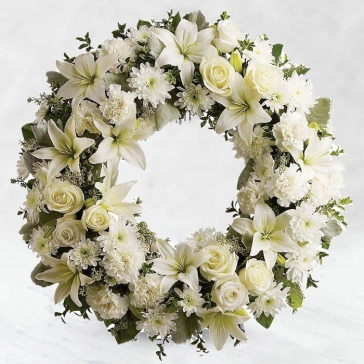 We offer a wreath of white blooms, designed by our florists, in tribute to your loved one and their natural heart and peaceful spirit. This peaceful gesture symbolizes the circle of everlasting life.
<br>Arranged as: 
Round Wreath Arrangement of 20 White Roses, 20 White Carnations, 10 Stems of Sivanthi, 6 Stems of White Lilies with green fillers and White Ribbons