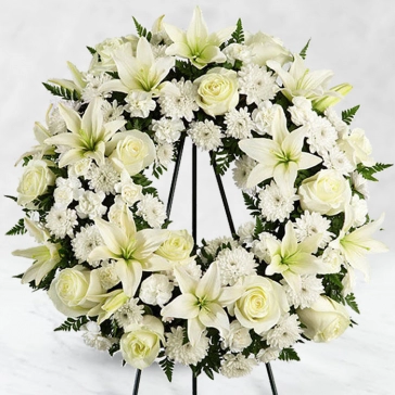 Memories shared with them are a comfort even after they are gone. This wreath is a lovely way to remember the ones you loved. Designed by professional florists from white floral blooms, the traditional funeral arrangement honors the ones you loved.
<br>Arranged as: 
Round Wreath Arrangement of 20 White Roses, 20 White Carnations, 5 Stems of Sivanthi, 6 Stems of White Lilies with green fillers and White Ribbons
